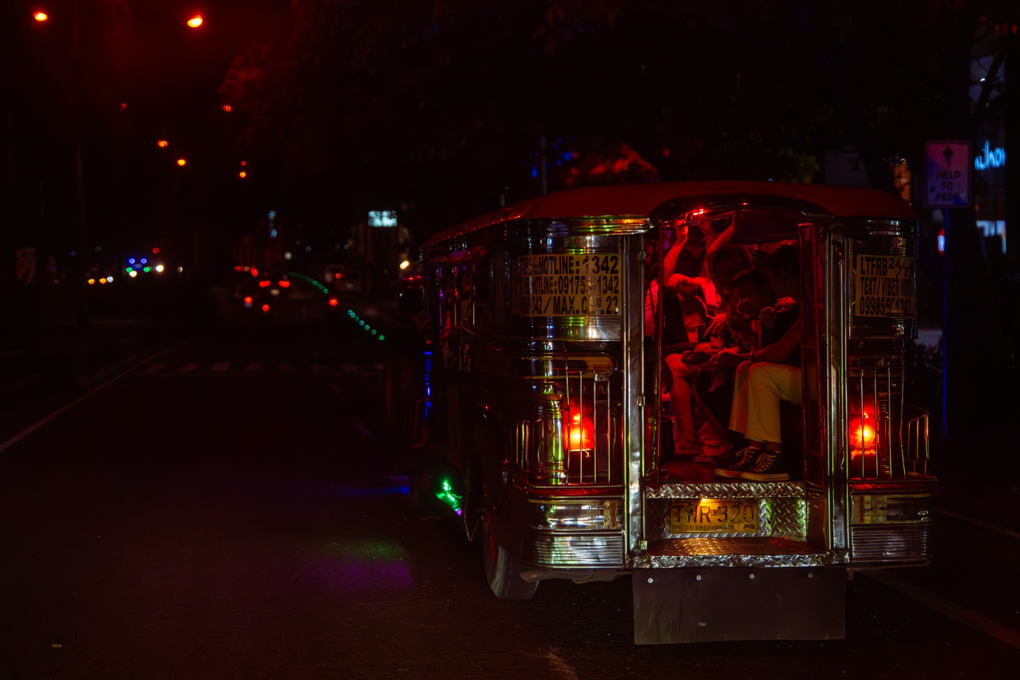 Jeepney glowing red on a street at night